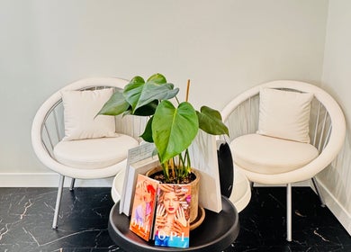 Relaxing waiting area with chairs at Sparadise, Calgary, Alberta, CA, featuring a stylish plant centerpiece.