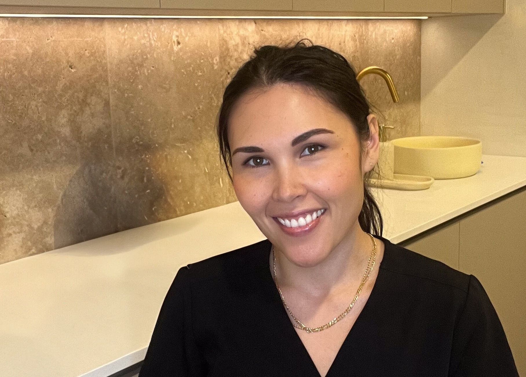 Professional at Nadine Aesthetics in Pacific Pines, Queensland, AU, smiling in a modern interior setting.