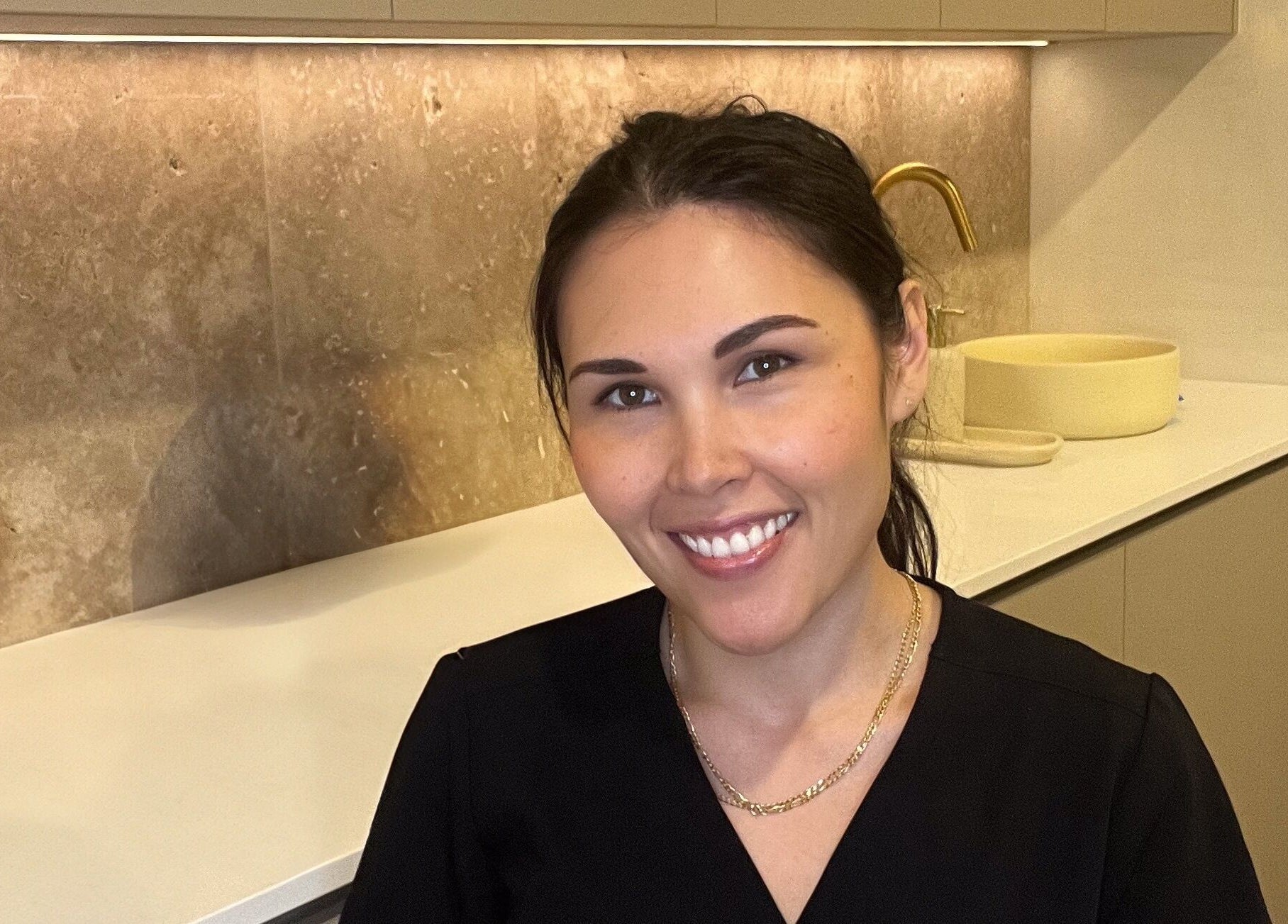 Professional at Nadine Aesthetics in Pacific Pines, Queensland, AU, smiling in a modern interior setting.