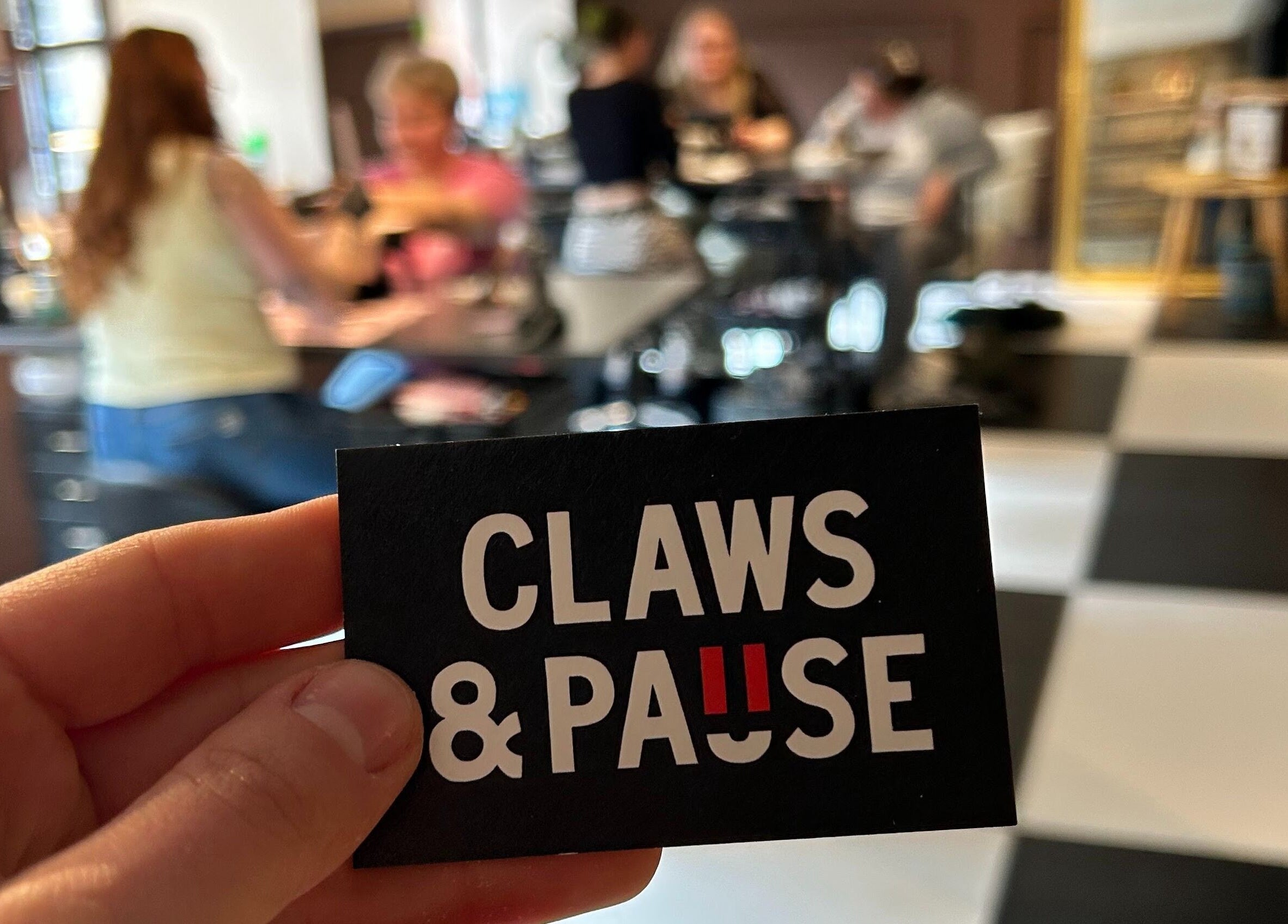 Claws and Pause venue card held at cozy group table in Edinburgh, Scotland, GB.