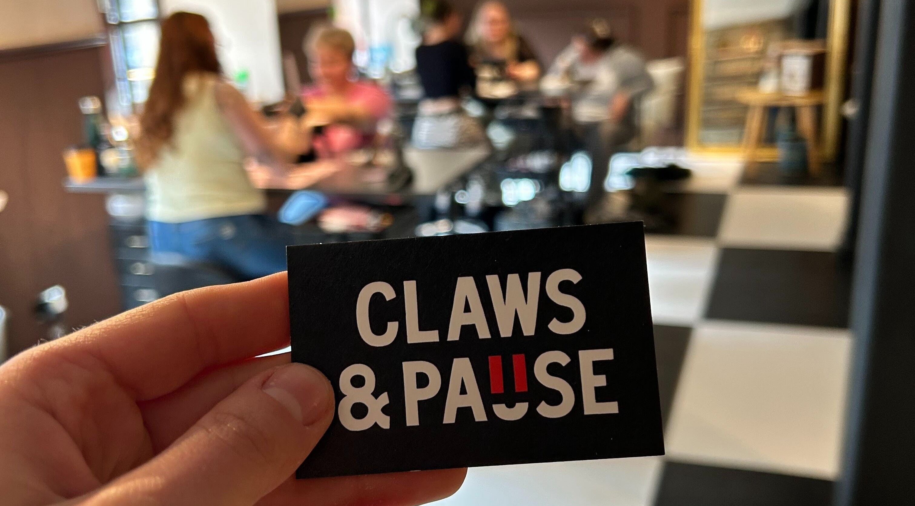 Claws and Pause venue card held at cozy group table in Edinburgh, Scotland, GB.
