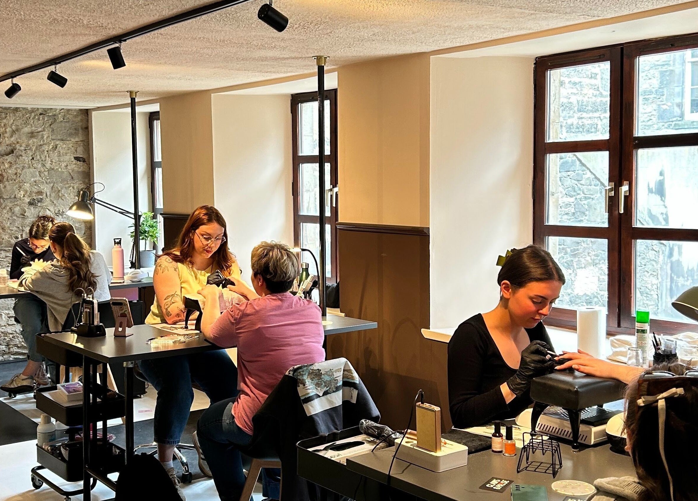 Clients enjoying nail services at Claws and Pause, Edinburgh, Scotland, GB with warm lighting and cozy decor.