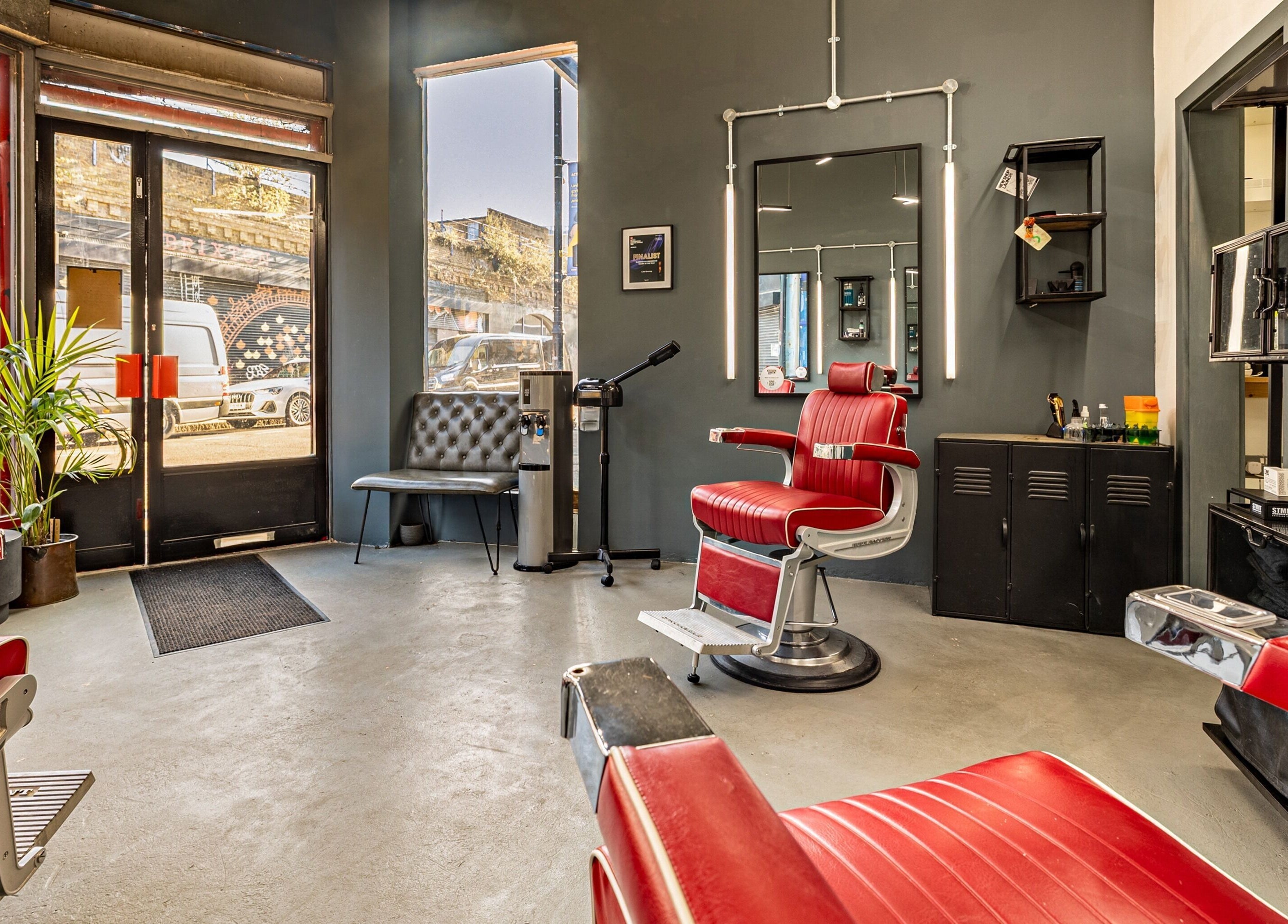 Interior of Curfew Grooming Brixton in London, England, GB showcasing stylish red barber chairs and modern decor.