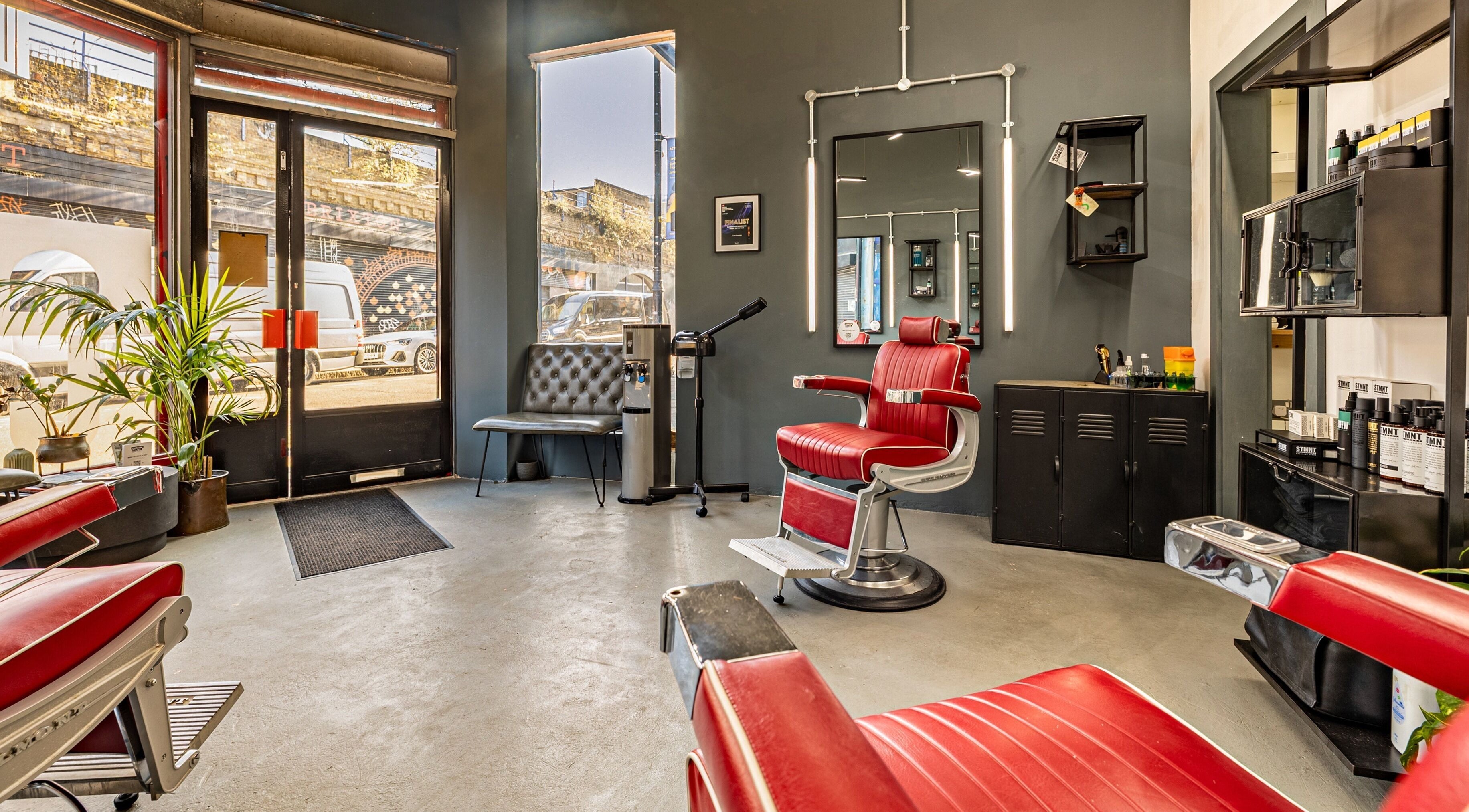 Interior of Curfew Grooming Brixton in London, England, GB showcasing stylish red barber chairs and modern decor.