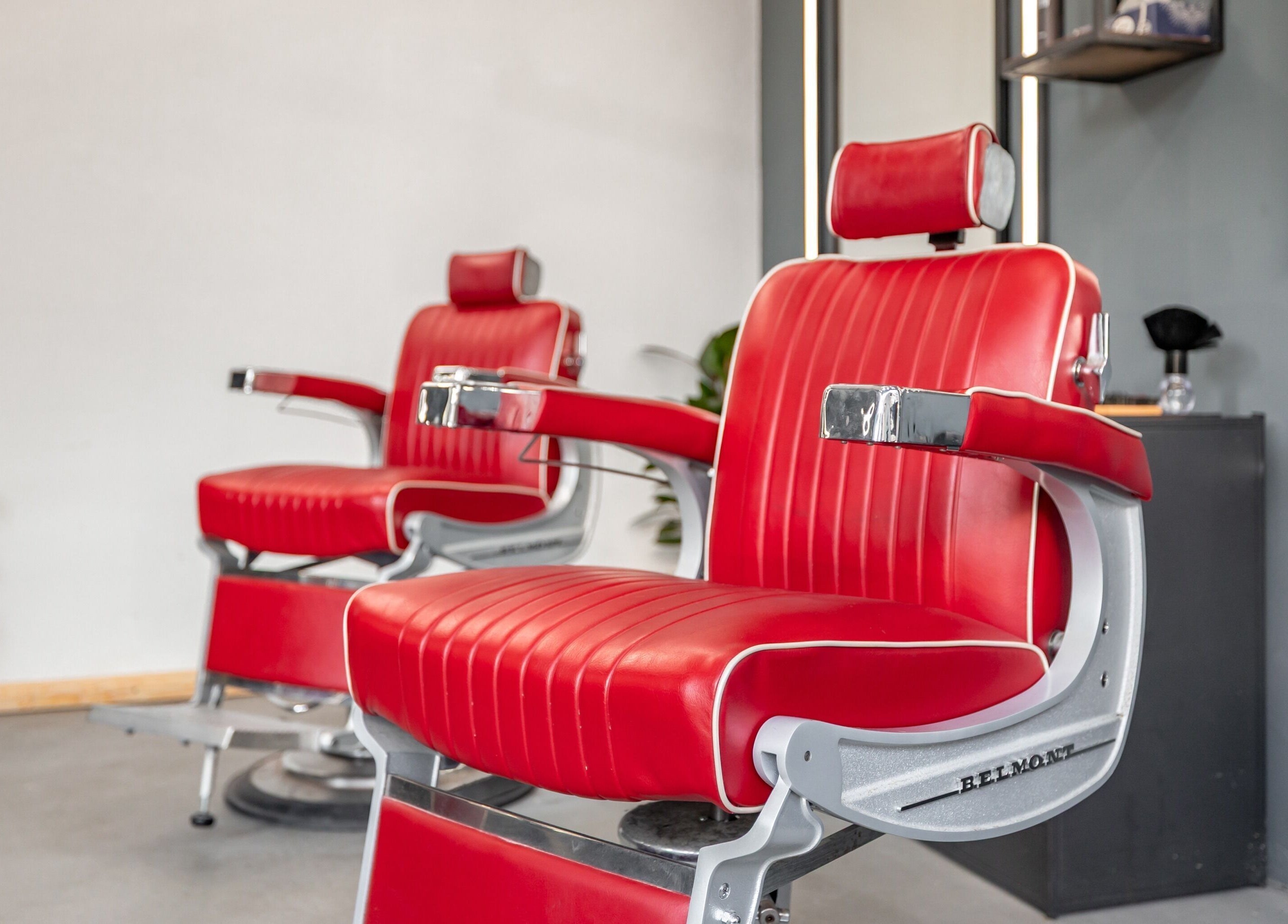 Red barber chairs at Curfew Grooming Brixton, London, England, GB offer a stylish grooming experience.