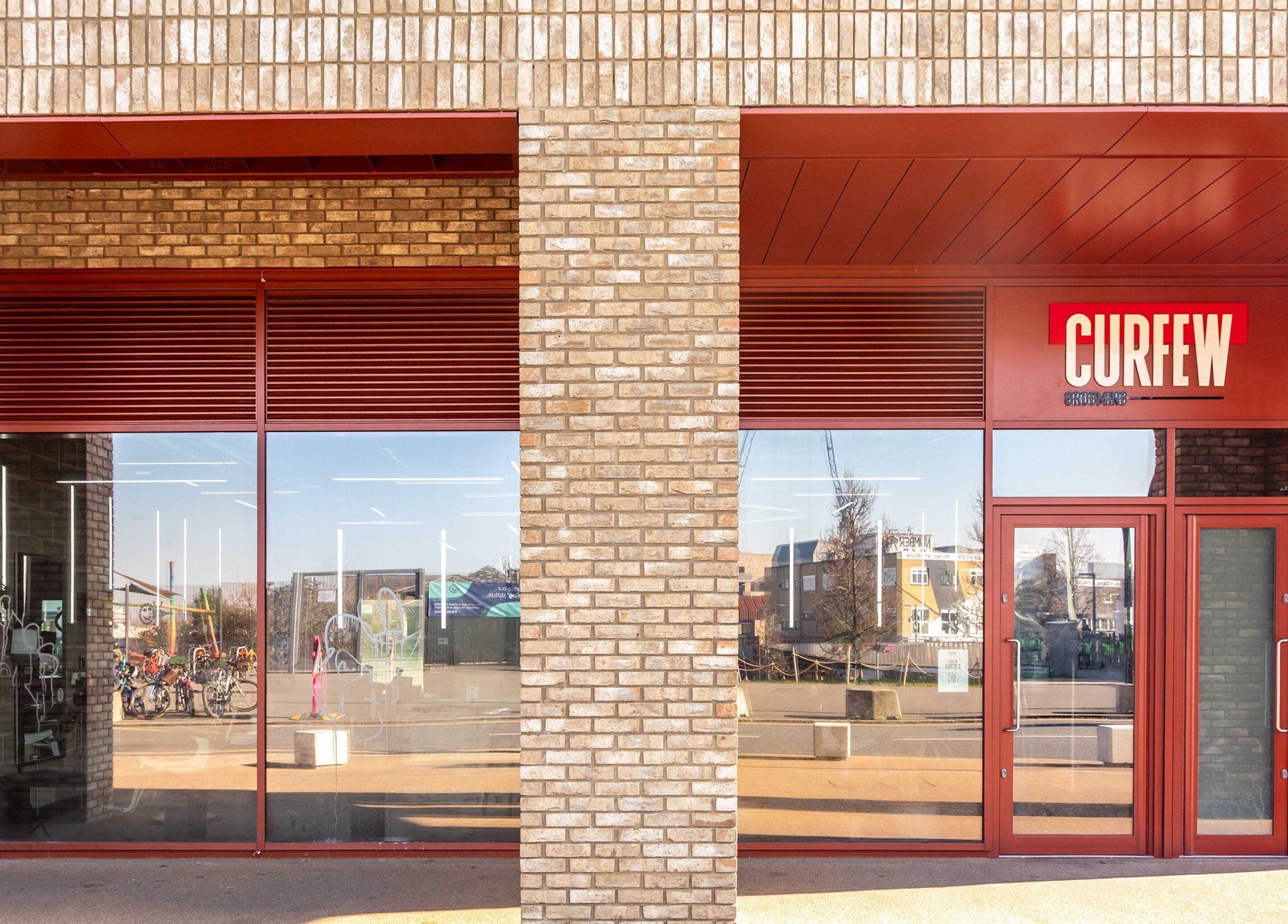 Exterior view of Curfew Grooming Hackney Wick in London, England, GB, featuring brick facade and large windows.
