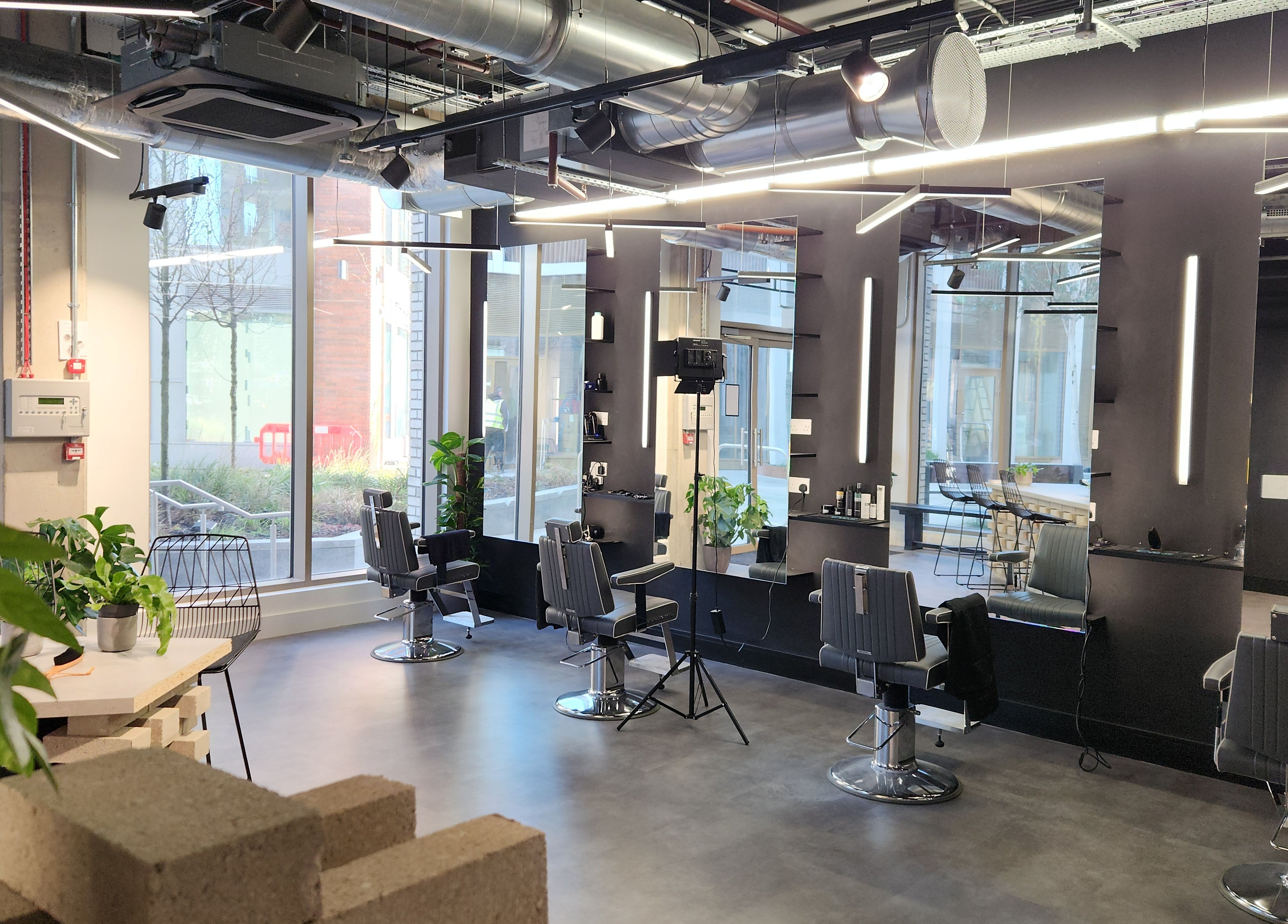 Spacious, modern salon interior at Curfew Grooming Wandsworth in London, England, GB showcasing sleek black chairs.