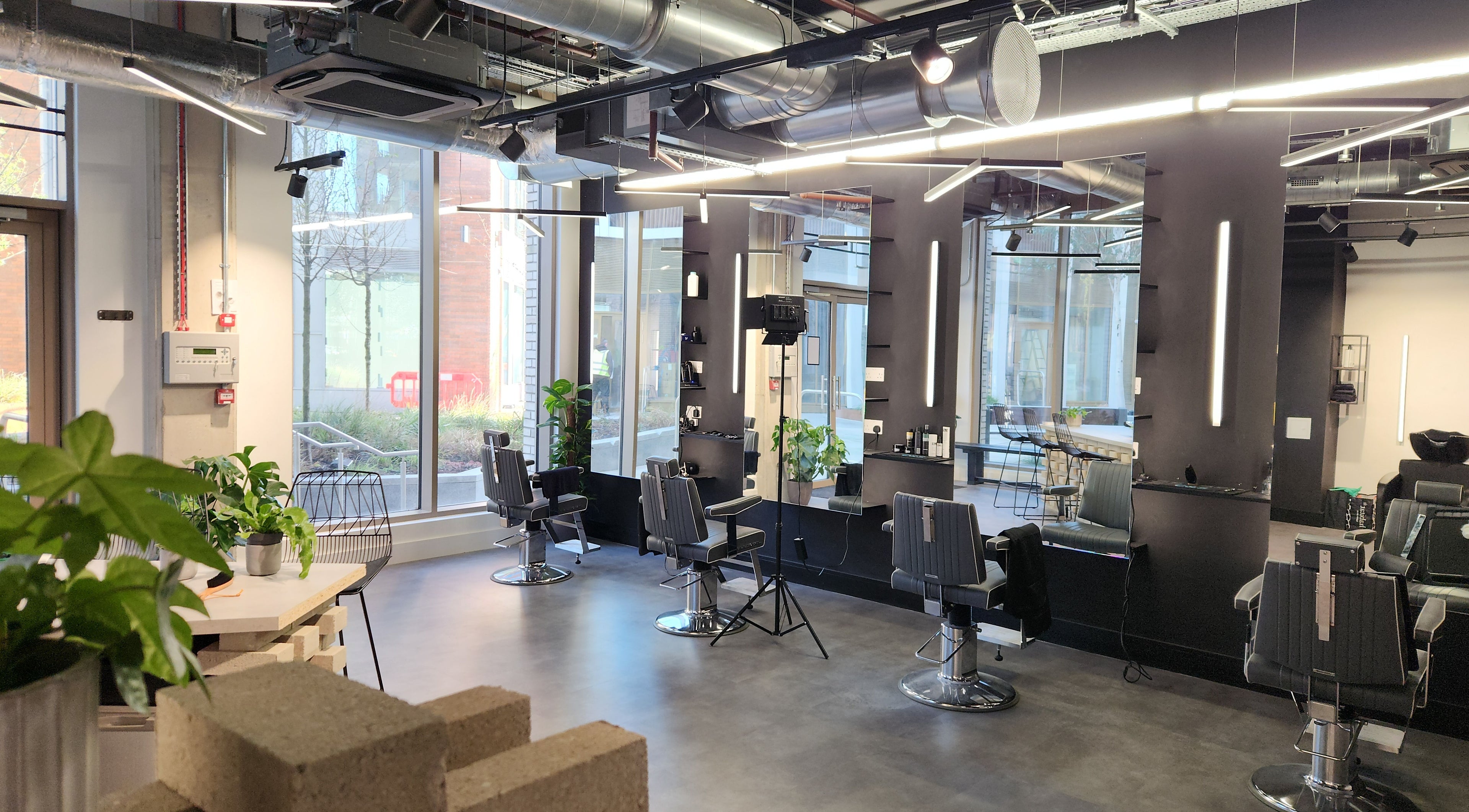 Spacious, modern salon interior at Curfew Grooming Wandsworth in London, England, GB showcasing sleek black chairs.