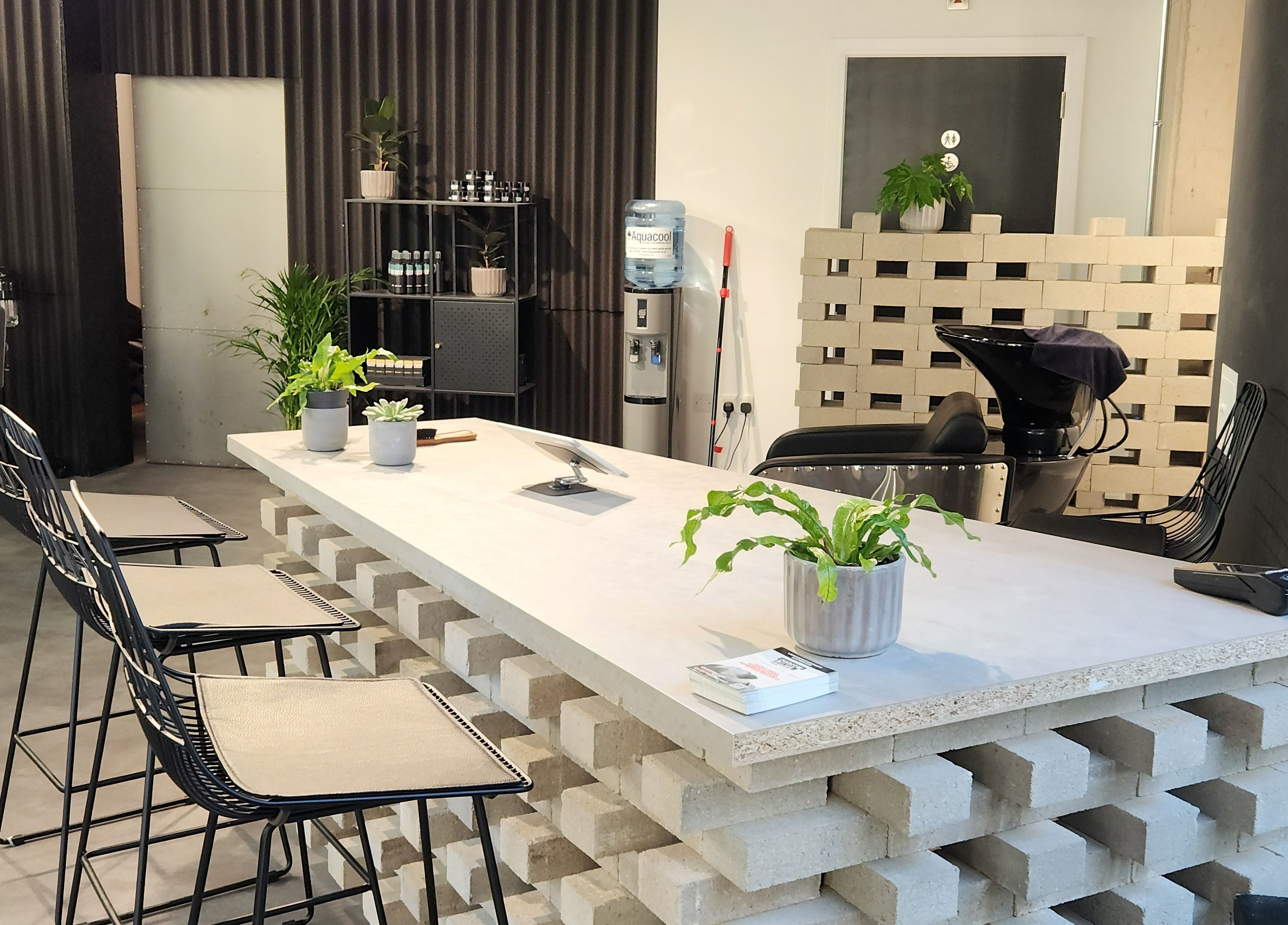 Modern interior of Curfew Grooming Wandsworth in London, England, GB with sleek chairs and lush plants.