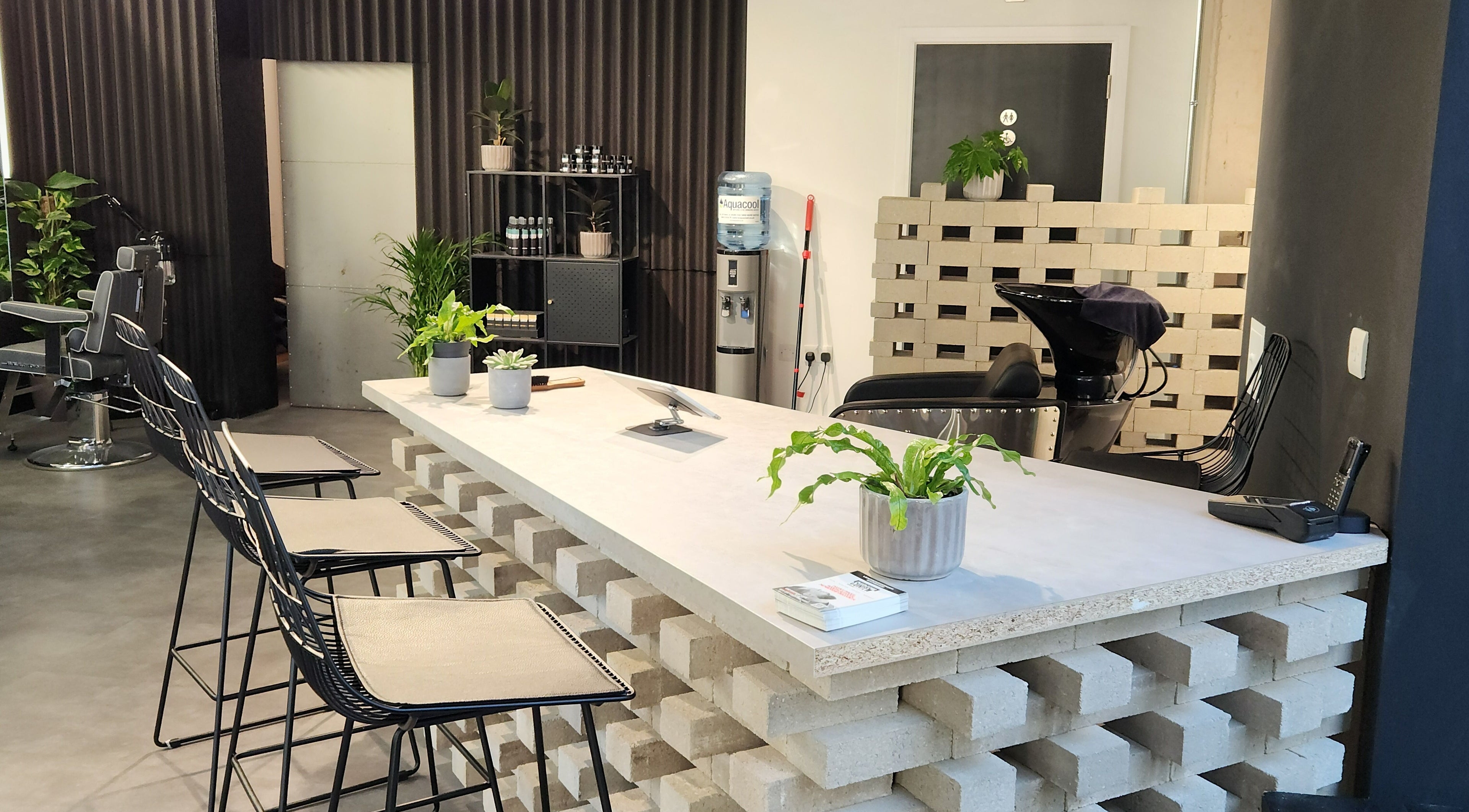 Modern interior of Curfew Grooming Wandsworth in London, England, GB with sleek chairs and lush plants.