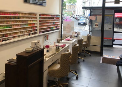 Interior of Ks Nail Salon in London, England, GB, showing manicure stations with vibrant polish displays.