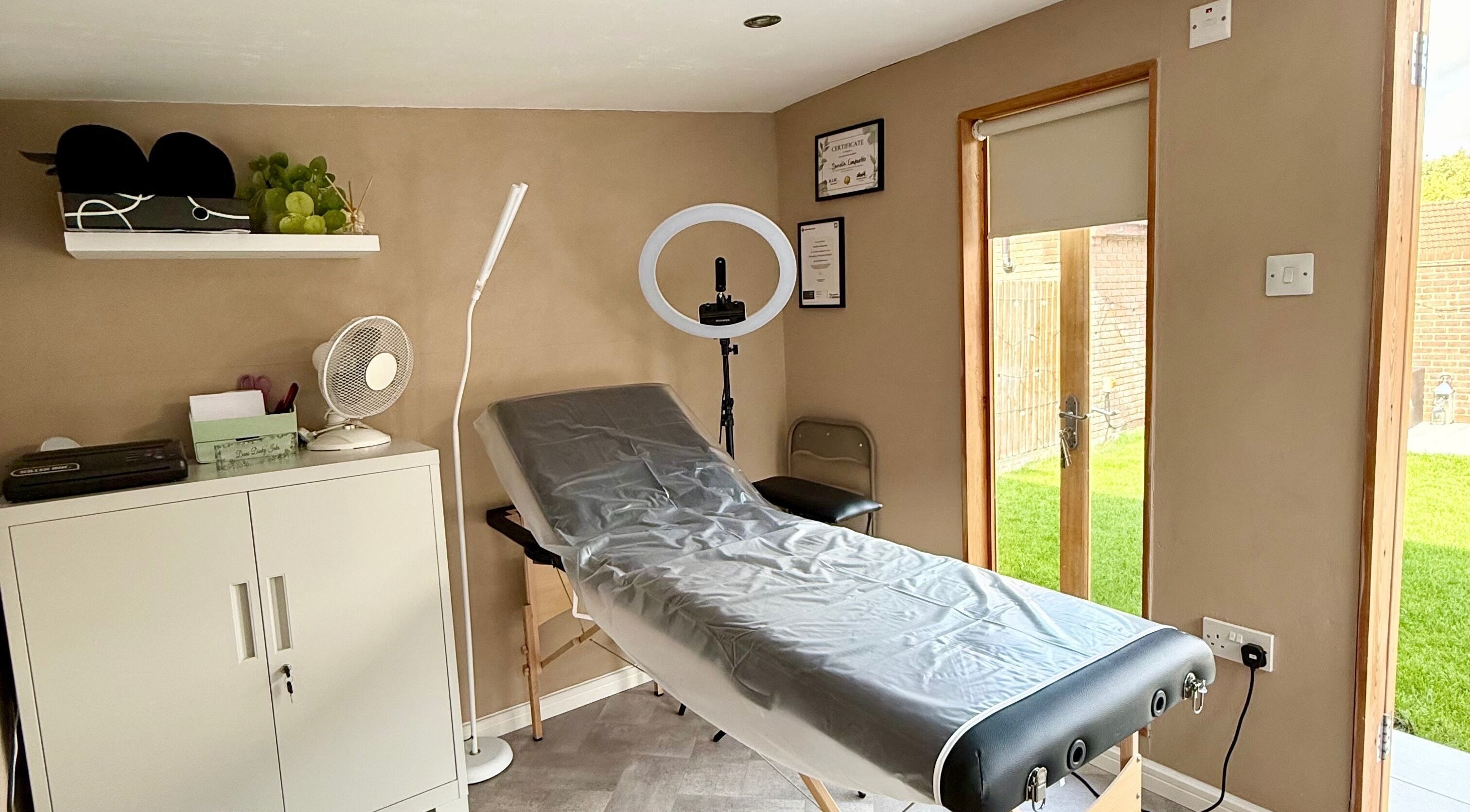 Cozy treatment room at Dinky Ink Studio in Bishop's Stortford, England, GB with massage table and ring light.