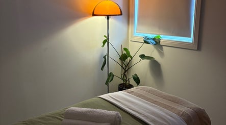 Cozy massage room at Sound and Bodywork Massage, Melbourne, Victoria, AU with soft lighting and a plant.