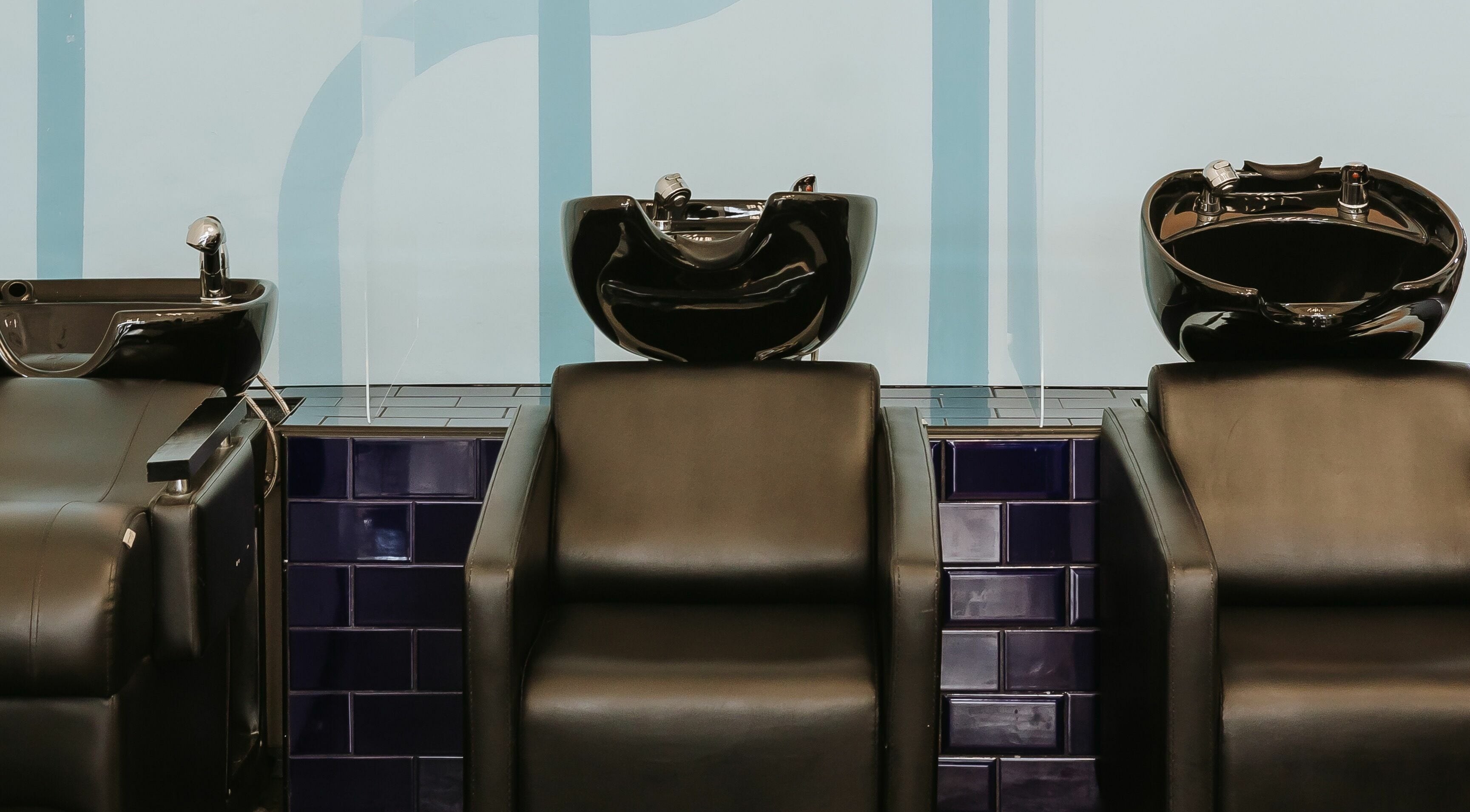 Modern hair wash stations at Salute Salon in Randburg, Gauteng, ZA with sleek black basins and comfortable chairs.