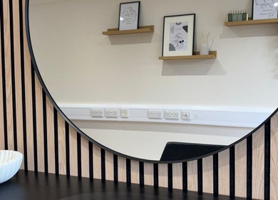 Stylish round mirror at Becky With The Good Hair - West End, Southampton, GB, reflecting elegant salon decor.