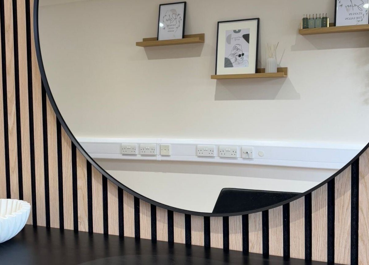 Stylish round mirror at Becky With The Good Hair - West End, Southampton, GB, reflecting elegant salon decor.