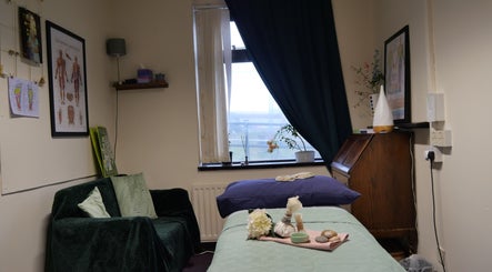 Cozy therapy room at Gyaltso Thugje Therapies in Alexandria, Scotland, GB, featuring a massage table and decor.