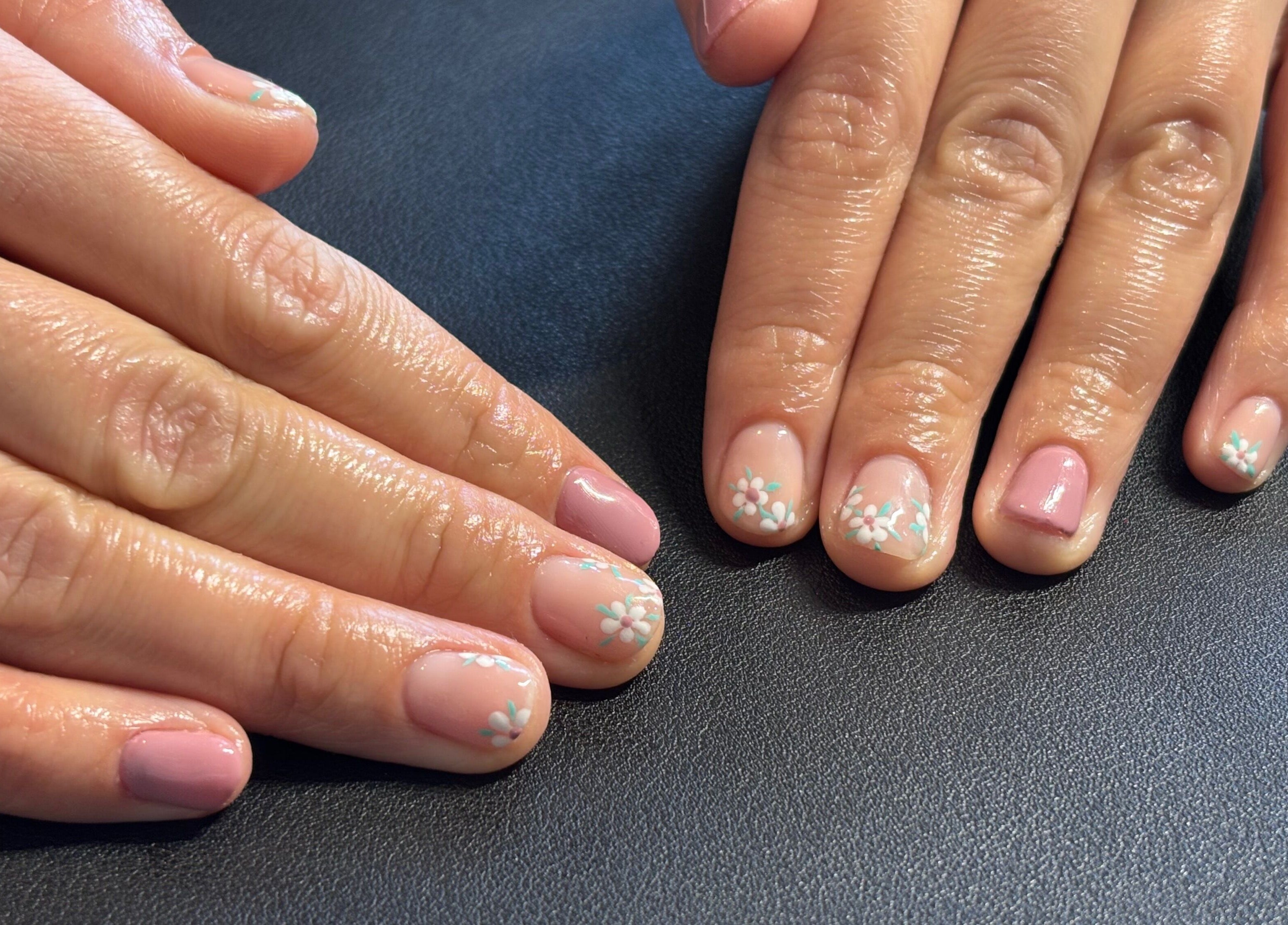 Elegant floral nail art at The Nail Room, Witchford, England, GB on a dark surface.