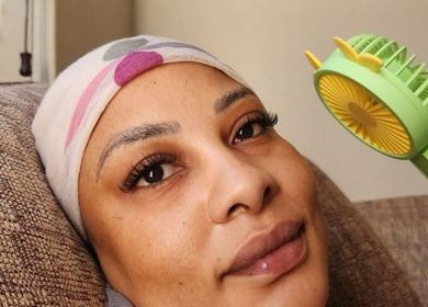 Woman with styled lashes relaxing at The Lash Shack, Randburg, Gauteng, ZA, holding a small fan.