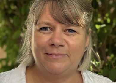Portrait of a relaxed, smiling woman at Relax & Glow, Swindon, England, GB, surrounded by lush greenery.
