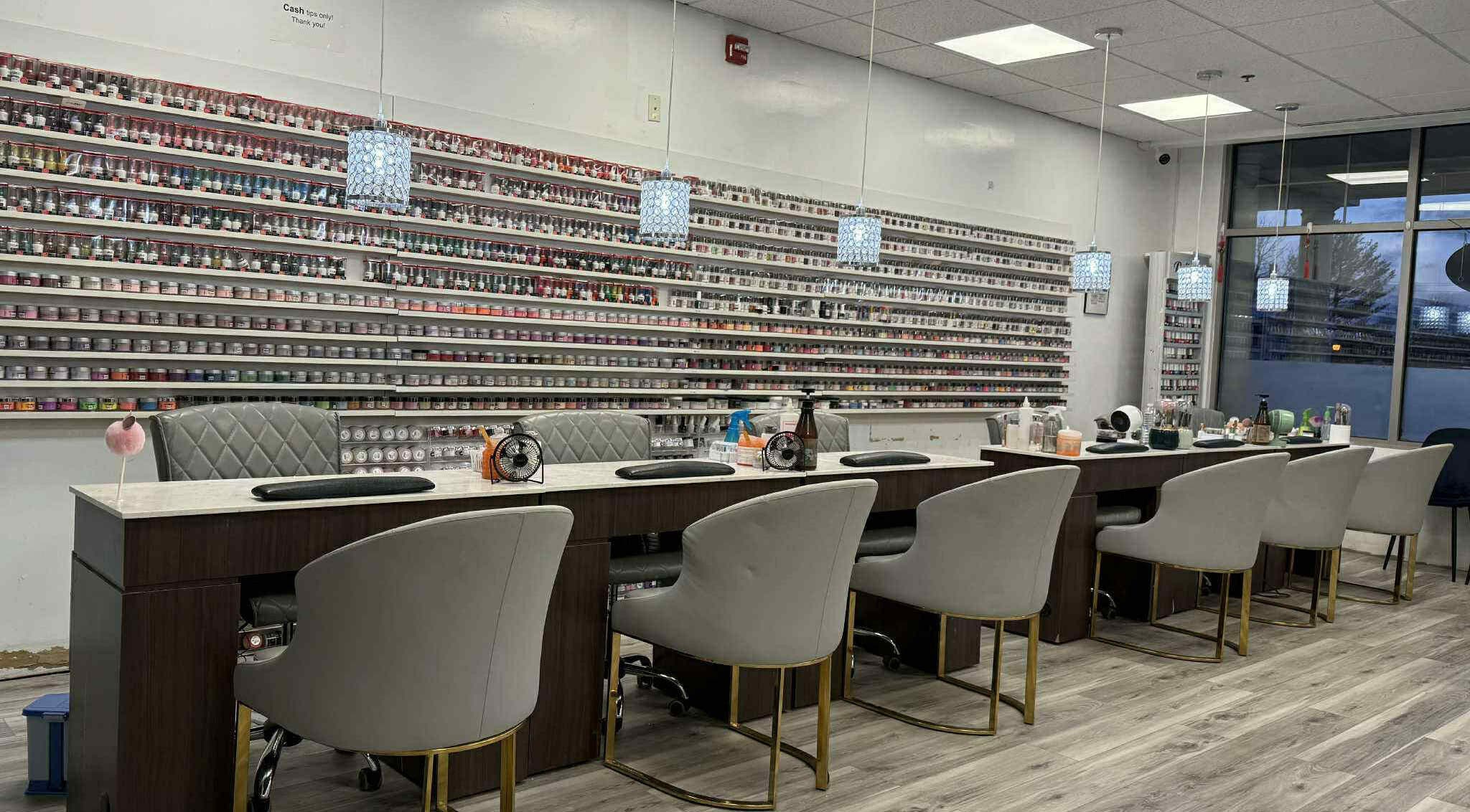 Contemporary nail salon interior at Fashion Nails, North Andover, Massachusetts, US with elegant seating and polish display.