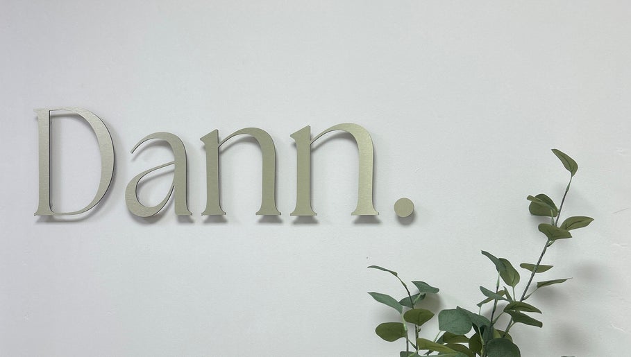 Elegant Dann Studio signage at Callierobinsonbrows AT DANN STUDIO, Plymouth, England, GB with green foliage.