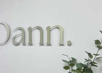 Elegant Dann Studio signage at Callierobinsonbrows AT DANN STUDIO, Plymouth, England, GB with green foliage.