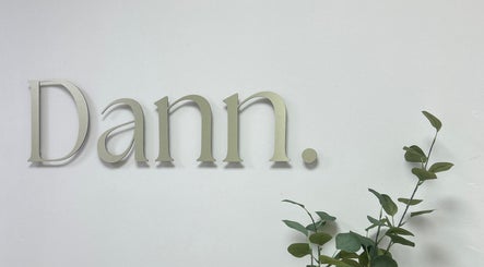 Elegant Dann Studio signage at Callierobinsonbrows AT DANN STUDIO, Plymouth, England, GB with green foliage.