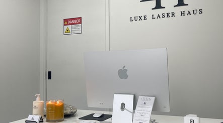 Reception desk at Luxe Laser Haus in Carnegie, Victoria, AU featuring an Apple computer and elegant decor.