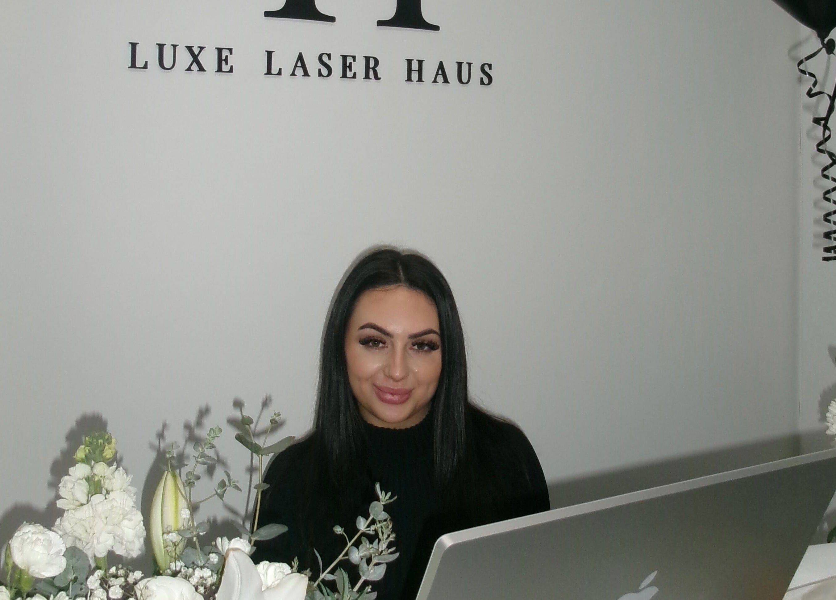 Receptionist at Luxe Laser Haus, Carnegie, Victoria, AU with elegant decor and flowers.