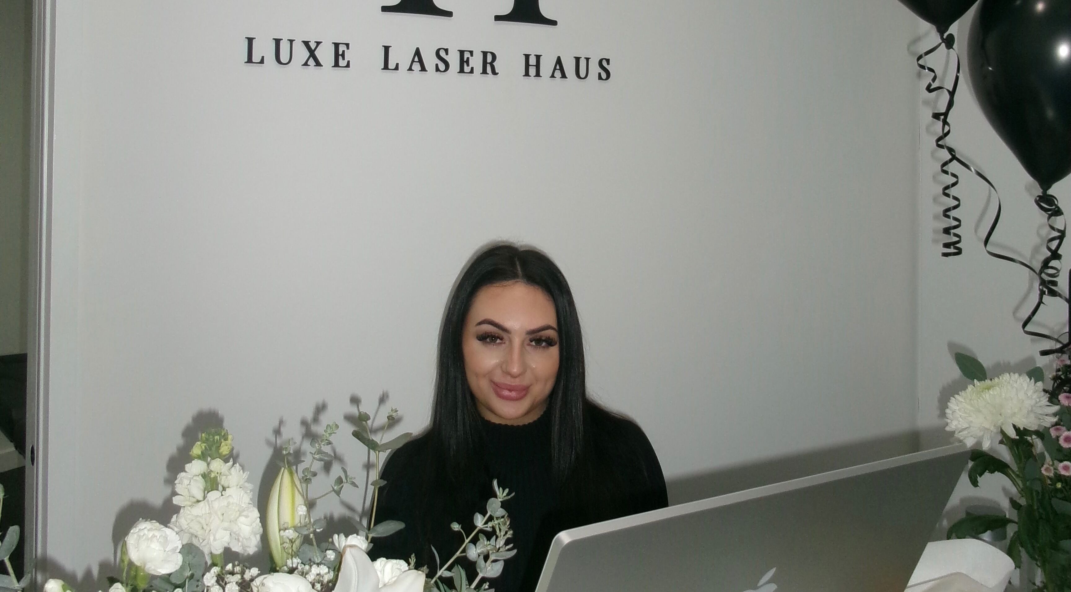 Receptionist at Luxe Laser Haus, Carnegie, Victoria, AU with elegant decor and flowers.