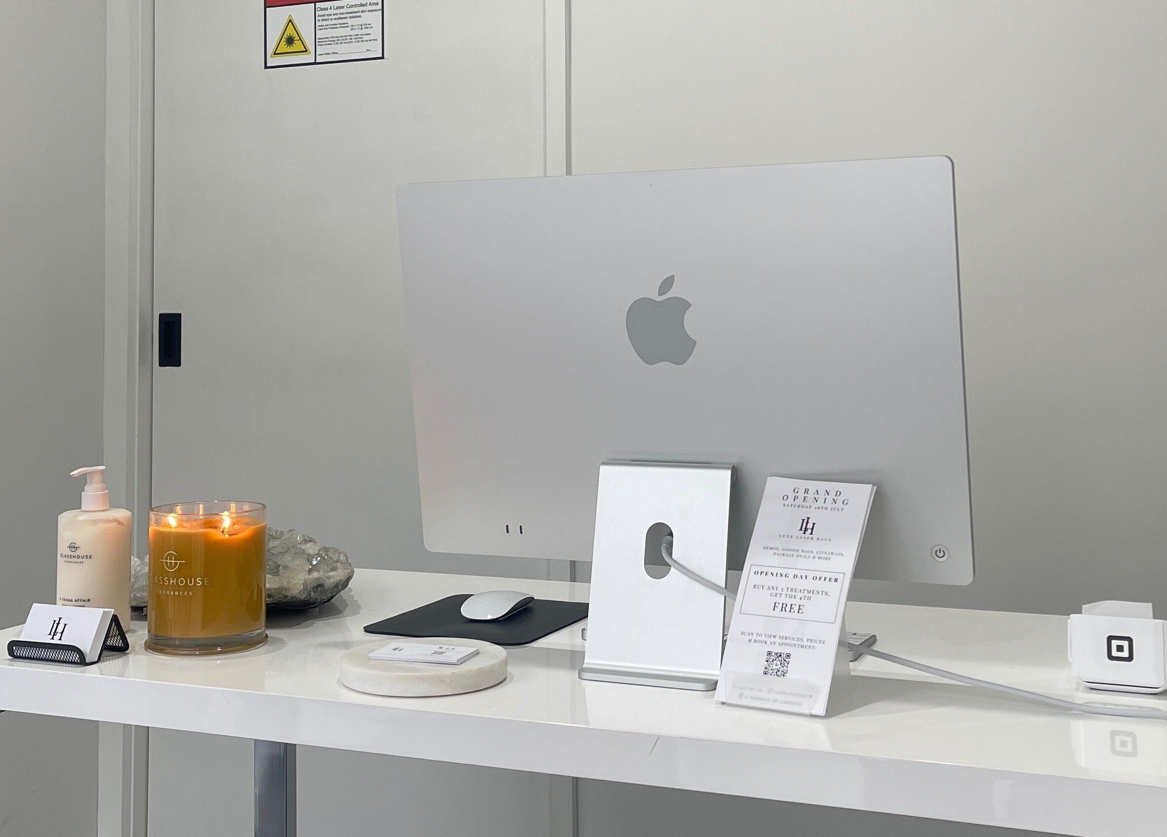 Luxe Laser Haus reception workspace in Carnegie, Victoria, AU with iMac, candle, and skincare products.