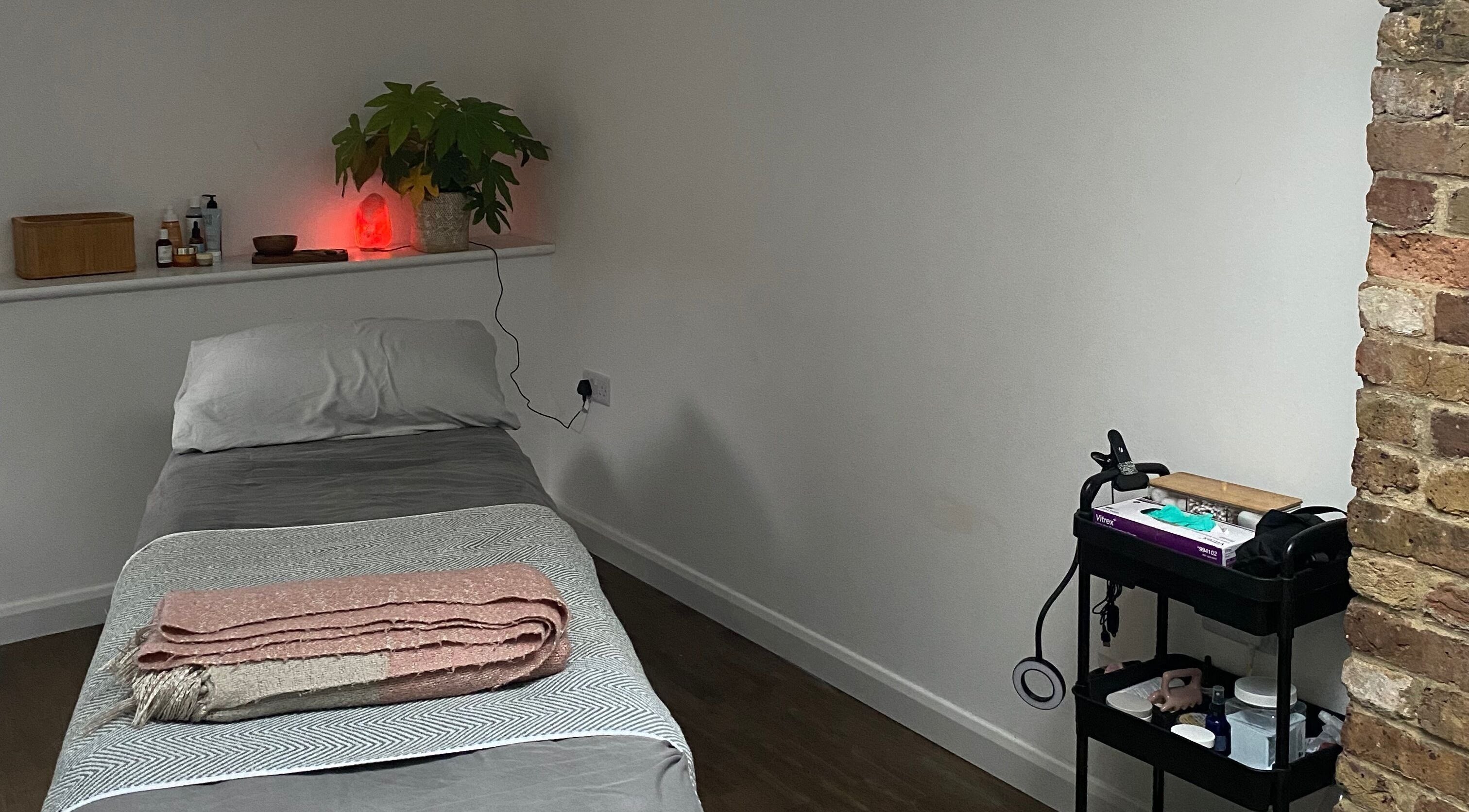 Cozy treatment room at Retreat Yourself Studio, Braintree, England, GB with massage table and soft lighting.