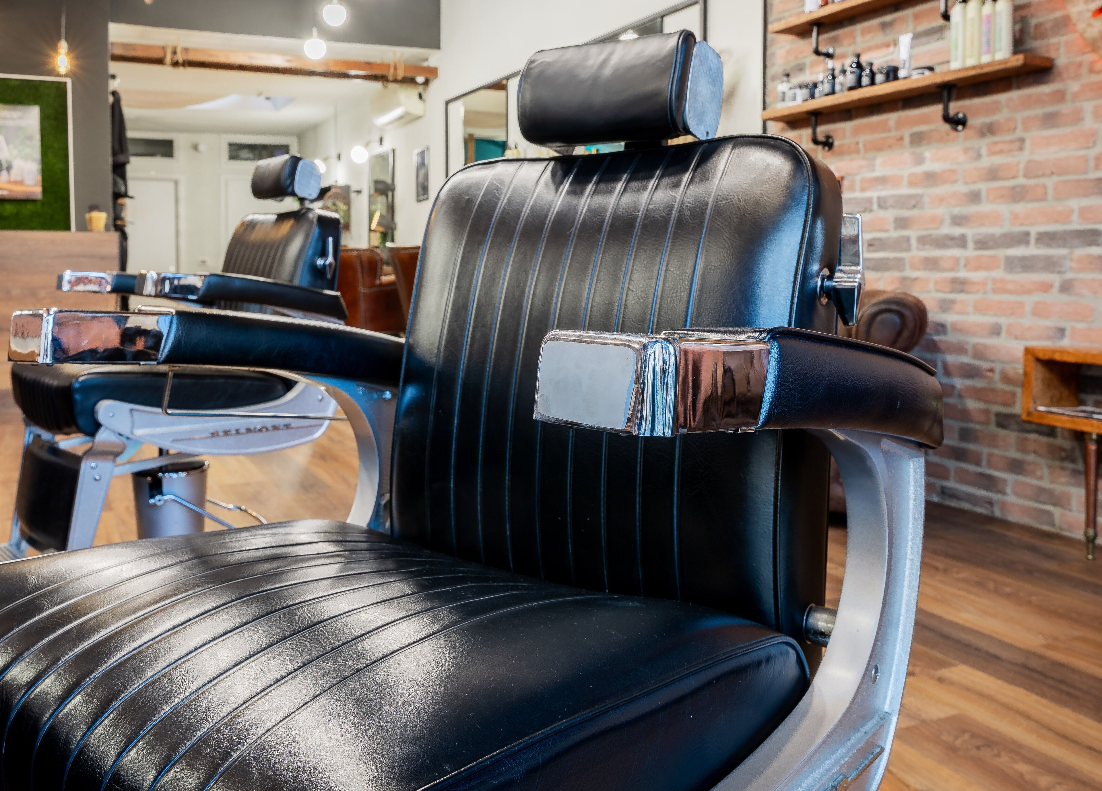 Poltrona da barbiere in pelle nera presso Baraka Salon, Este, Veneto, IT. Stile e comfort unici.