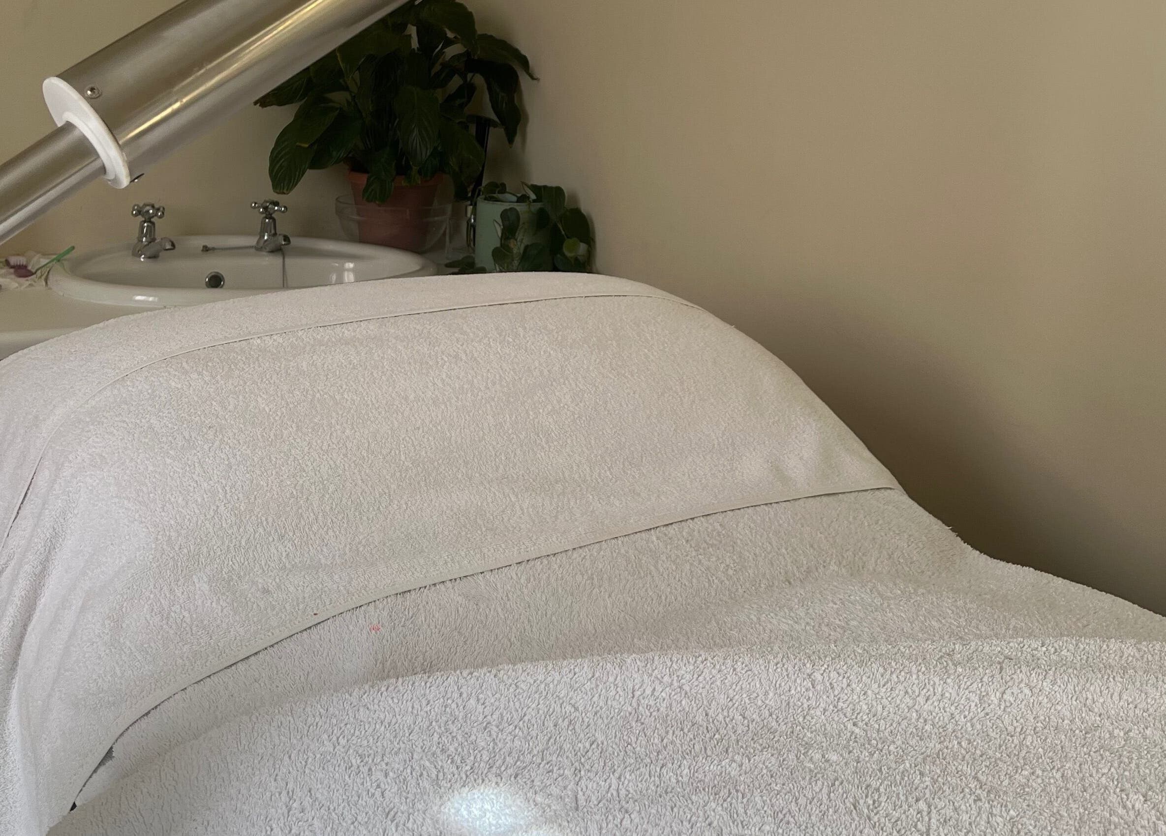 Calming spa treatment room at Jessie Beauty, Cape Town, Western Cape, ZA with massage bed and sink.