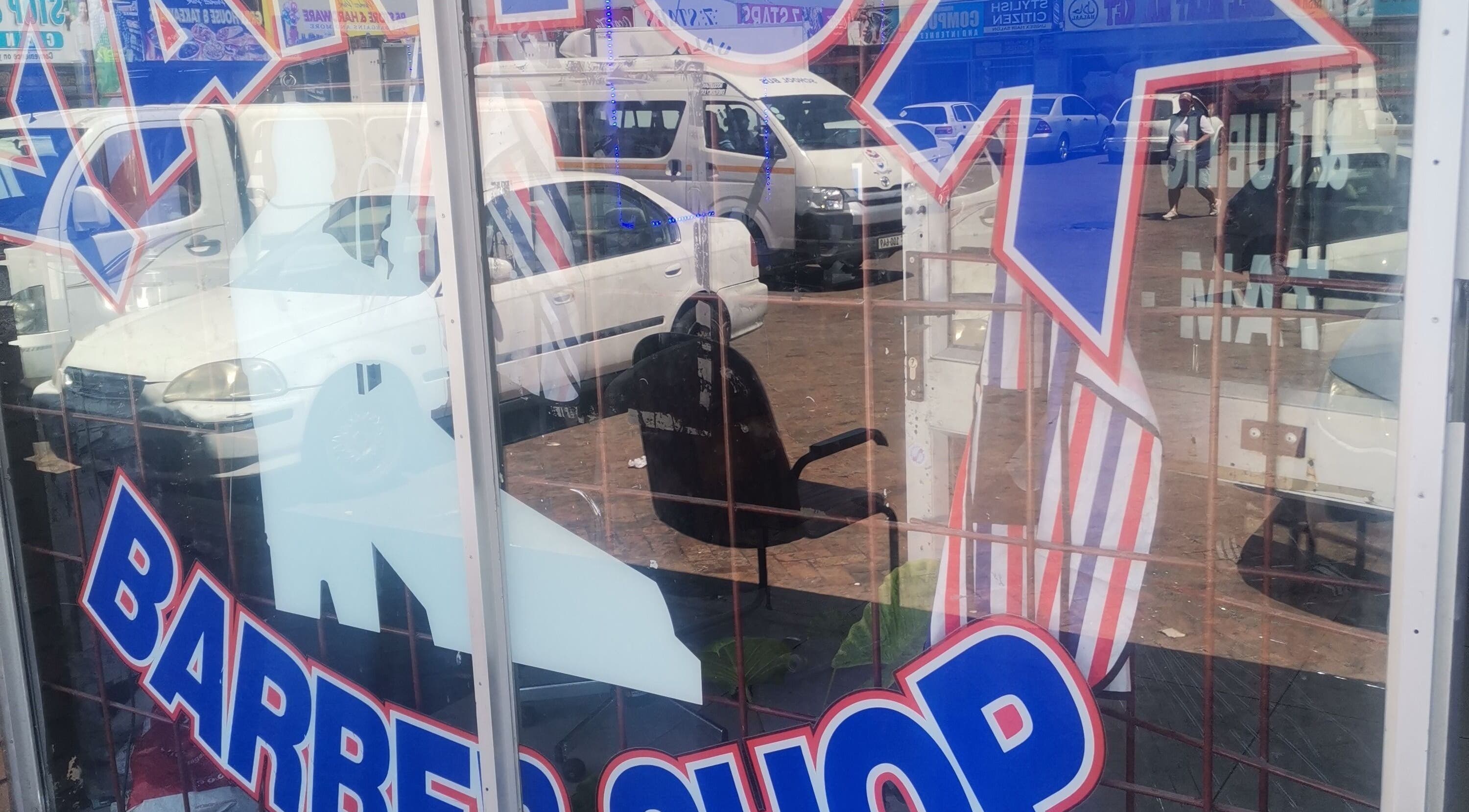 Street-facing barber shop window at C's_Cuts in Cape Town, Western Cape, ZA with a busy urban reflection.