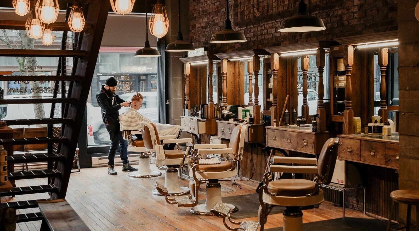 Victory Barber & Brand Gastown in Vancouver, BC features rustic interiors with a skilled barber at work.