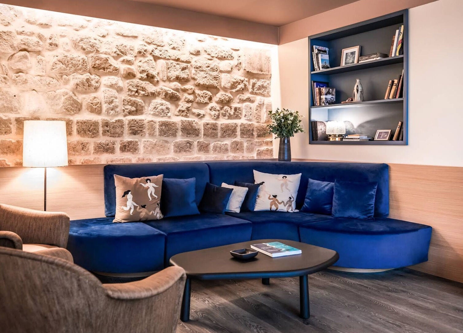 Coin salon moderne et confortable à Spa Clēmēns, Paris, Île-de-france, FR, avec canapé bleu et murs en pierre.