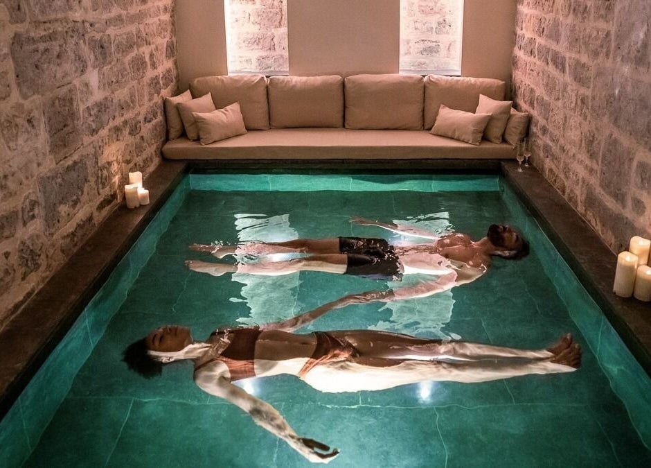 Relaxation dans un bain flottant au Spa Clēmēns, Paris, Île-de-France, FR. Ambiance paisible avec des bougies.