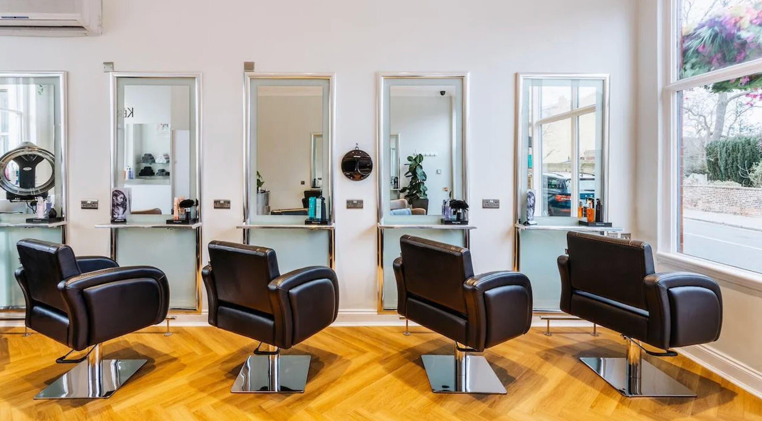 Elegant interior of Making Waves Salon, London, England, GB, showcasing four sleek styling chairs and mirrors.