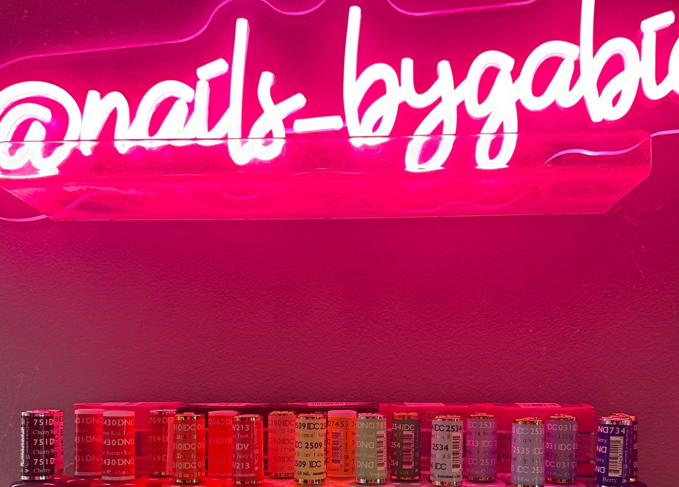 Vibrant neon sign of Nails By Gabie with colorful polishes in Bettendorf, Iowa, US.