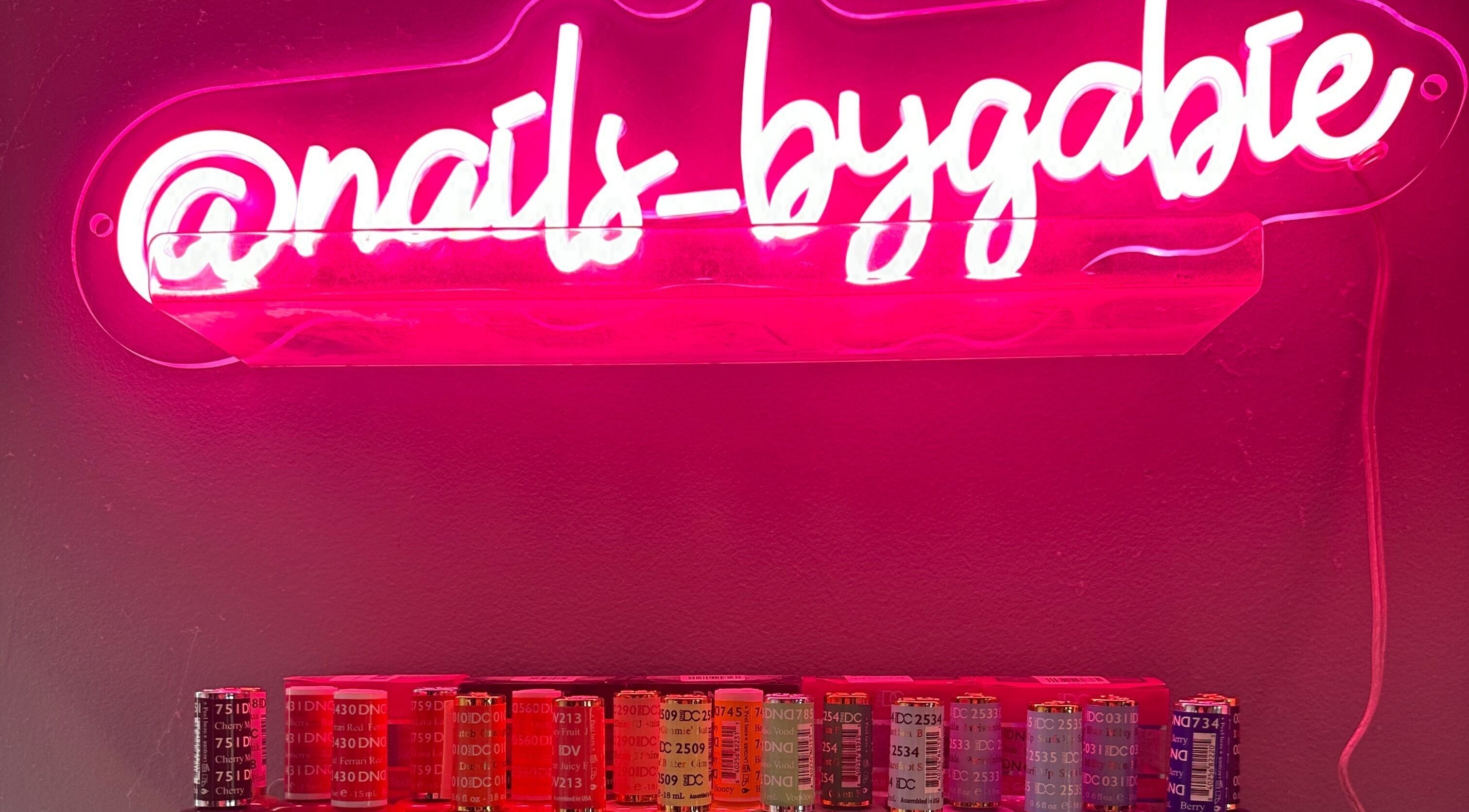 Vibrant neon sign of Nails By Gabie with colorful polishes in Bettendorf, Iowa, US.