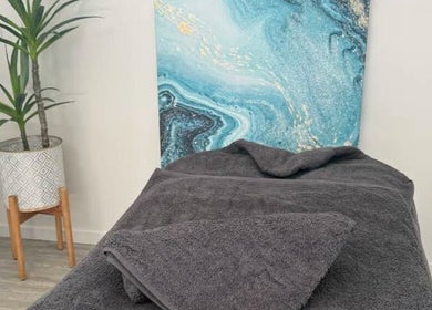 Relaxing massage room at Massage Relax Restore Townsville, Garbutt, Queensland, AU, featuring plush towels and art.