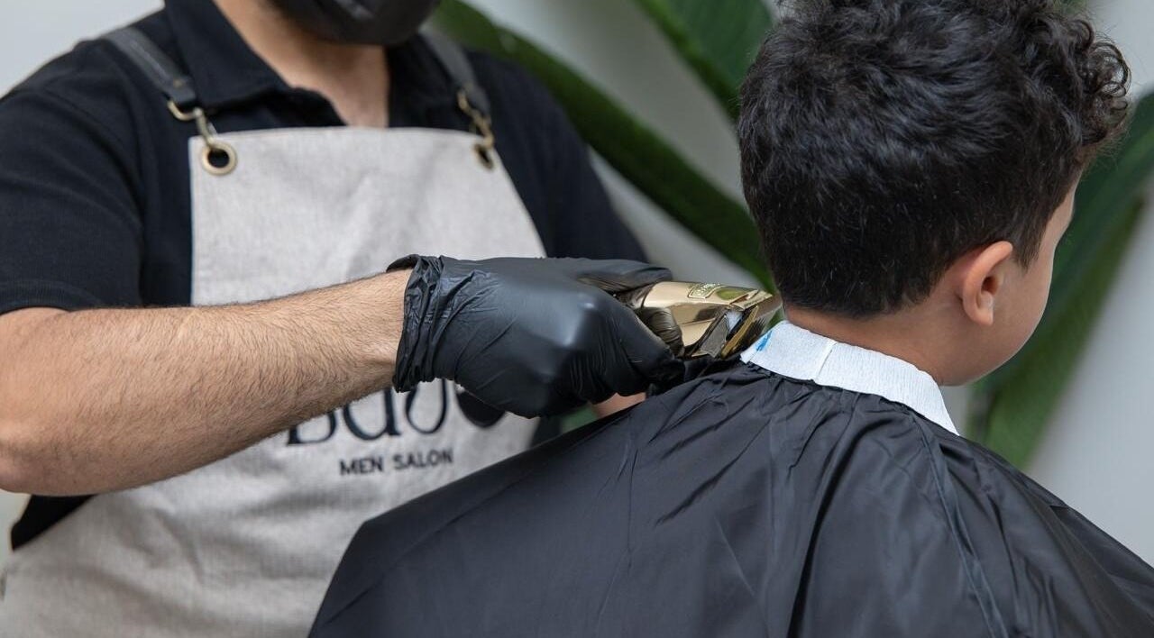 Barber giving a haircut at Lujo Barbershop, Al Khobar, Eastern Province, SA while wearing gloves.