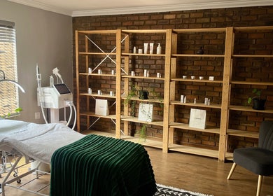 Relaxing treatment room at Haze Aesthetics, Centurion, Gauteng, ZA with a comfortable spa bed and wooden shelves.