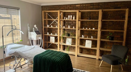 Relaxing treatment room at Haze Aesthetics, Centurion, Gauteng, ZA with a comfortable spa bed and wooden shelves.