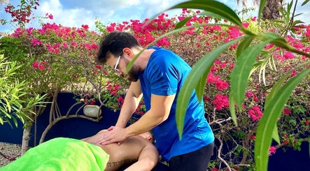 Outdoor massage at Bahia Relaxation Spa & Massage Curaçao, Willemstad, Curaçao, CW, surrounded by lush flowers.