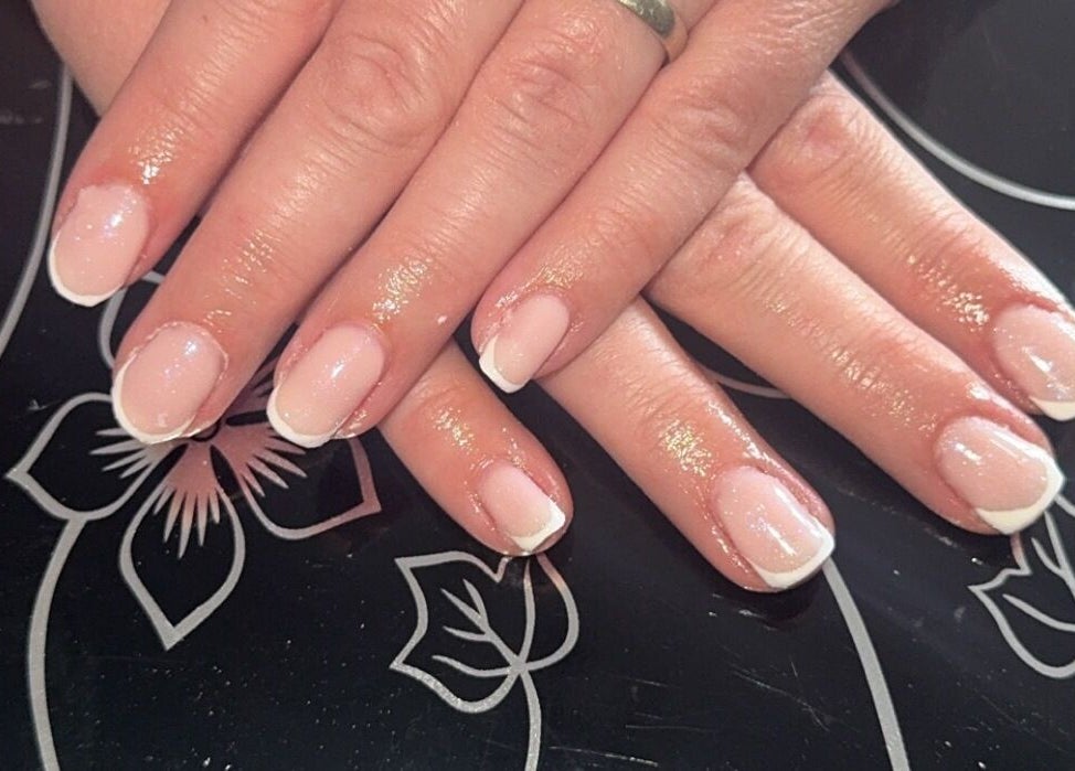 Elegant French manicure at Beauté Bar, Dumfries, Scotland, GB. Perfectly polished nails on floral backdrop.