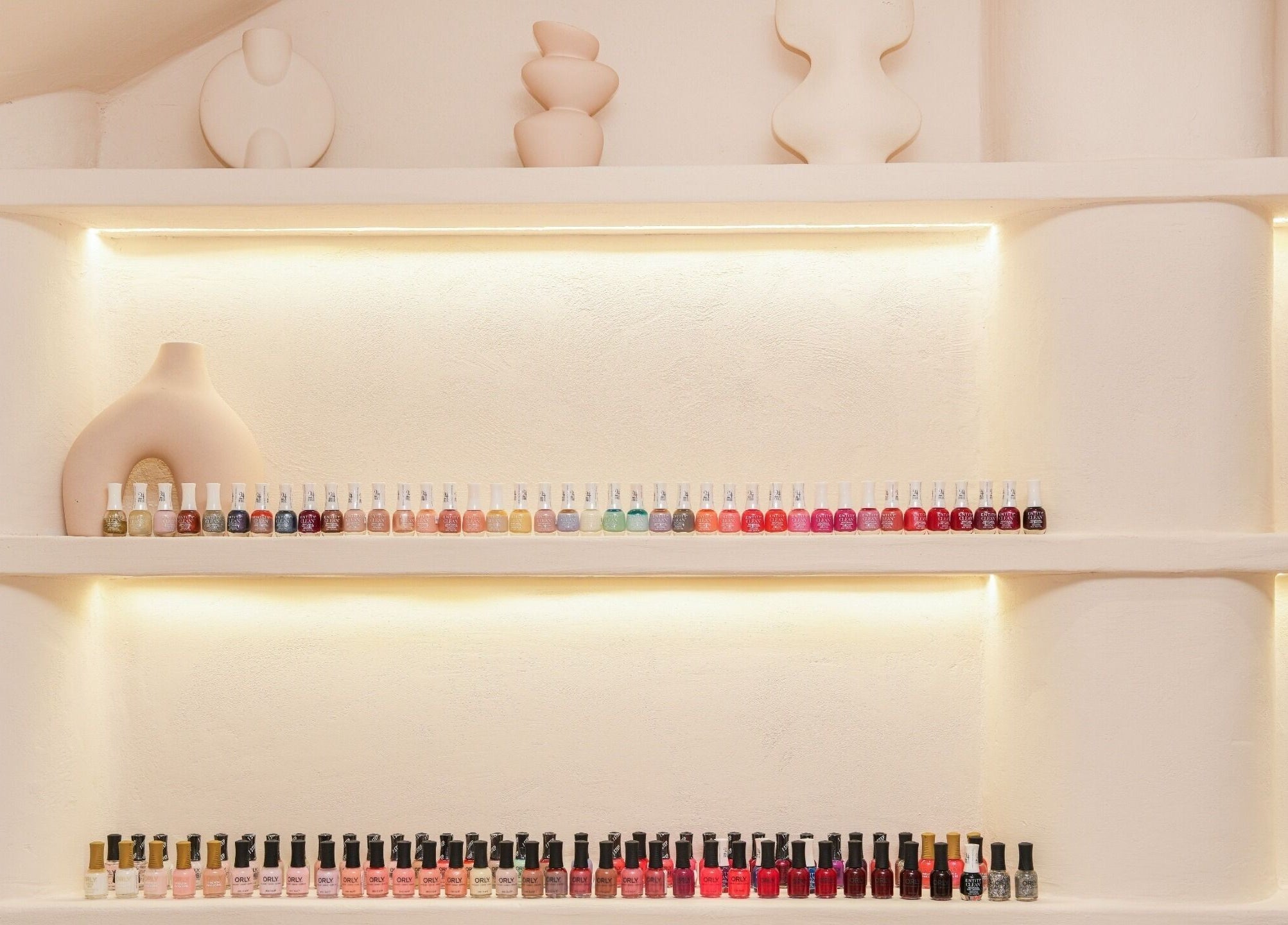 Nail polish display at The Edit Studio, Jeddah, Makkah Province, SA, showcasing vibrant colors on illuminated shelves.