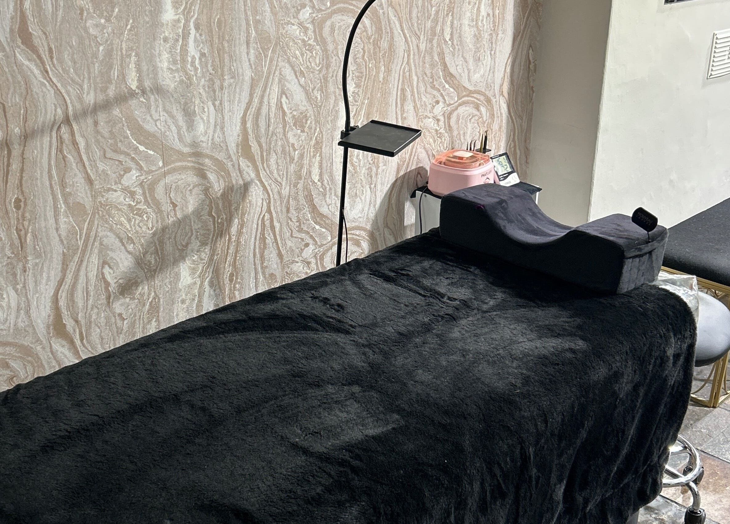 Relaxing treatment room at JMBeauty in Brayton, England, GB with a plush black massage table.